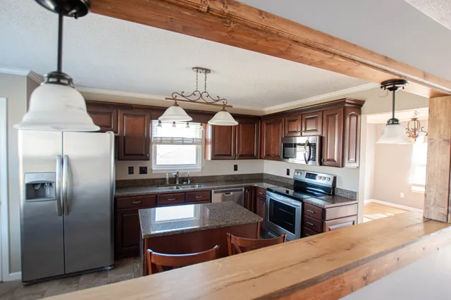 a kitchen with stainless steel appliances granite countertop a sink a stove and refrigerator