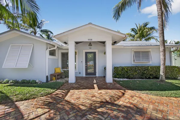 a front view of a house with a yard and potted plants
