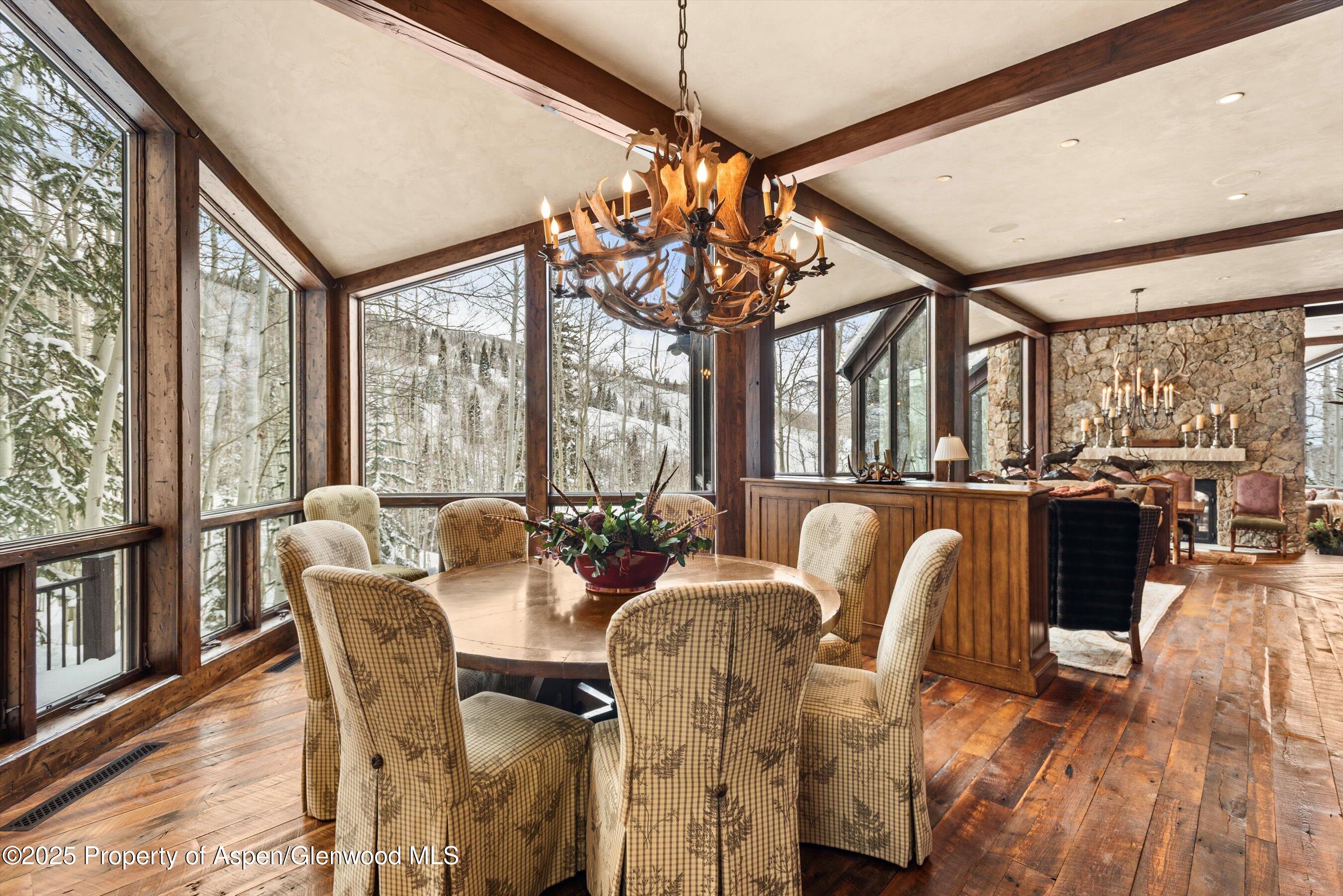 1777 Wood Road Snowmass Village, CO 81615 - Photo 5 of 27 a view of a dining room with furniture large windows and wooden floor