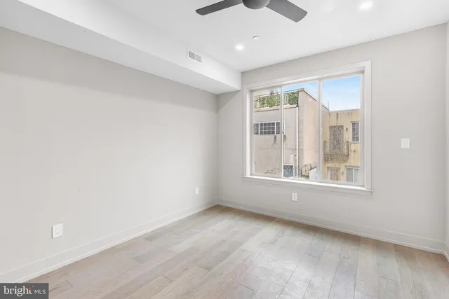 a view of an empty room with a window and wooden floor