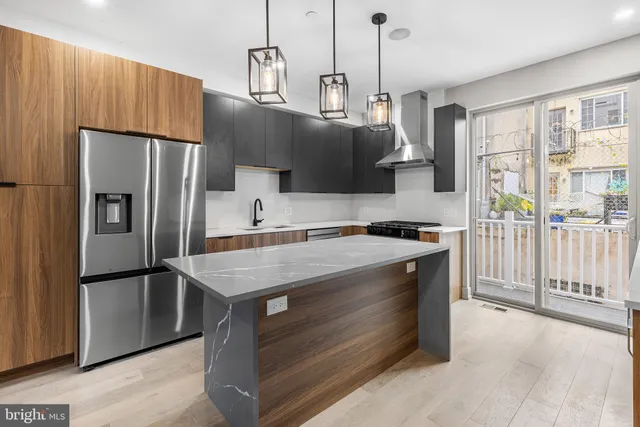 a kitchen with kitchen island a counter top a stove a refrigerator and a view of living room