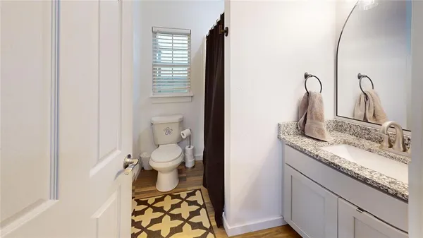 a bathroom with a granite countertop sink toilet and a mirror