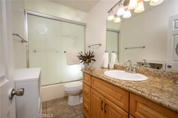 a bathroom with a granite countertop sink a toilet a mirror and shower