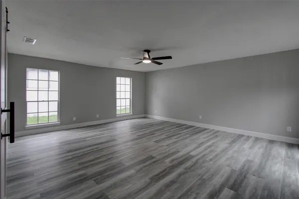 an empty room with wooden floor and windows