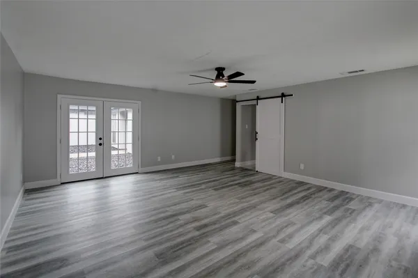 a view of an empty room with a window and wooden floor