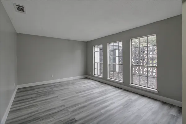a view of an empty room with wooden floor and fan