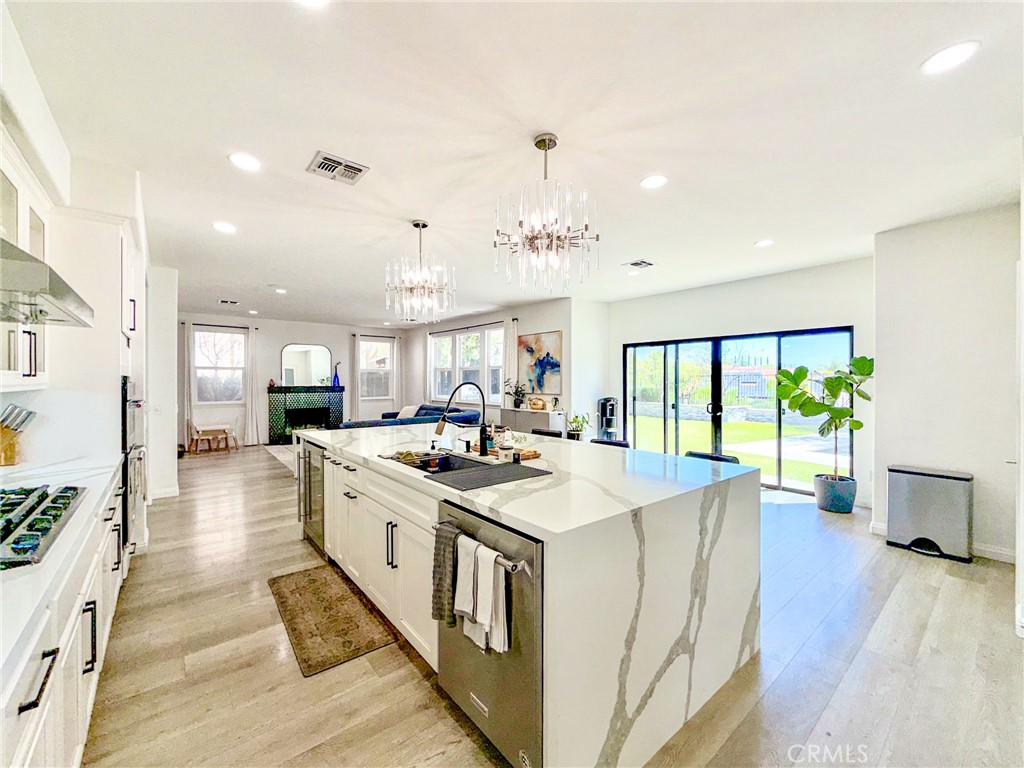 25714 Wallace Place Stevenson Ranch, CA 91381 - Photo 3 of 24 a large white kitchen with wooden floor and stainless steel appliances