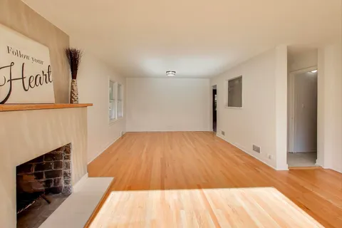a view of empty room with wooden floor and fireplace