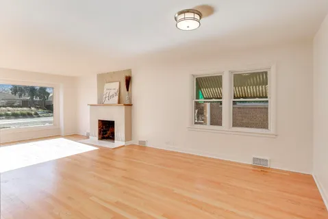 a view of empty room with wooden floor and fireplace