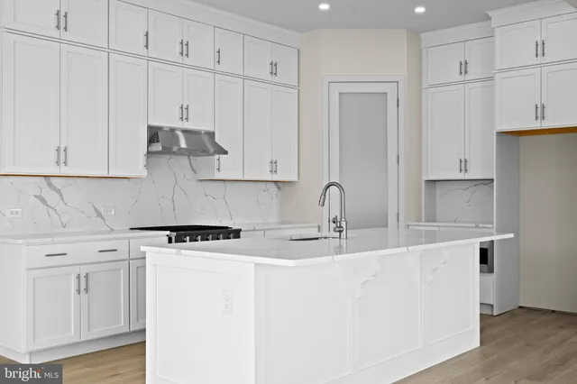 a kitchen with stainless steel appliances granite countertop a sink stove and white cabinets with wooden floor