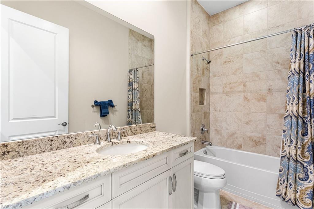 7825 Hawthorne Drive, Unit 2104 Naples, FL 34113 - Photo 26 of 43 a bathroom with a granite countertop sink a toilet a mirror a bathtub and shower