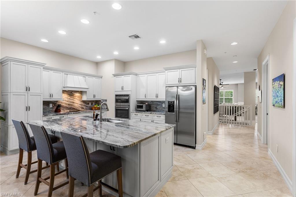 7825 Hawthorne Drive, Unit 2104 Naples, FL 34113 - Photo 6 of 43 a kitchen with stainless steel appliances granite countertop a table chairs sink refrigerator and microwave