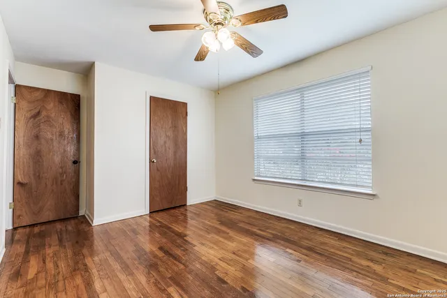a view of an empty room with wooden floor and a window