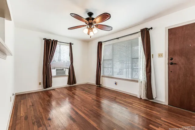 a view of an empty room with wooden floor and a window