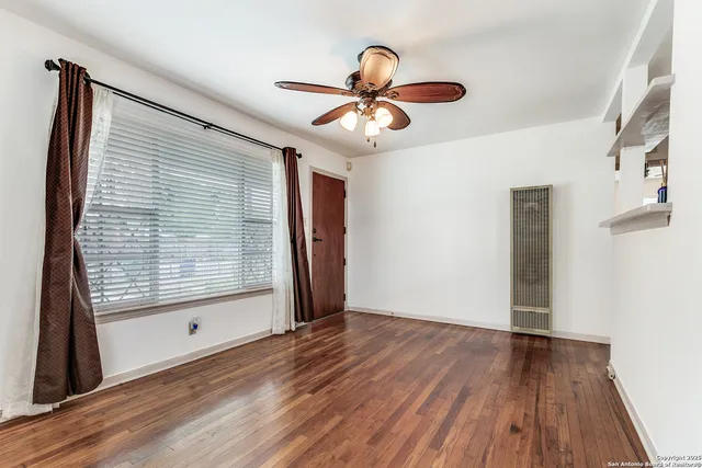 a view of an empty room with wooden floor and a window