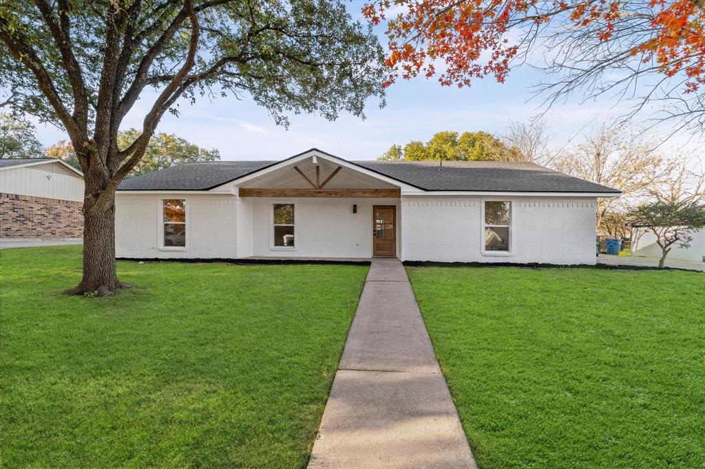 View of front of house with brick siding, a front lawn, a porch, and roof with shingles
