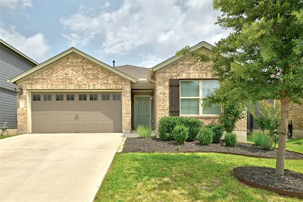a view of yellow house with a big yard and potted plants