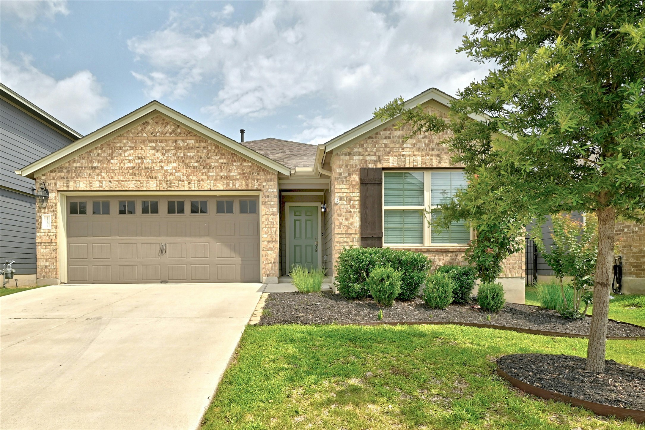a view of yellow house with a big yard and potted plants