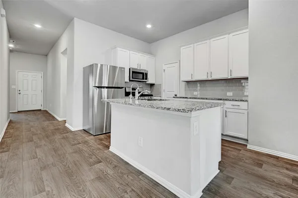a kitchen with kitchen island granite countertop a sink cabinets and stainless steel appliances