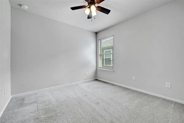 an empty room with windows and ceiling fan