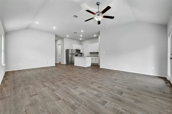 an empty room with wooden floor and a ceiling fan