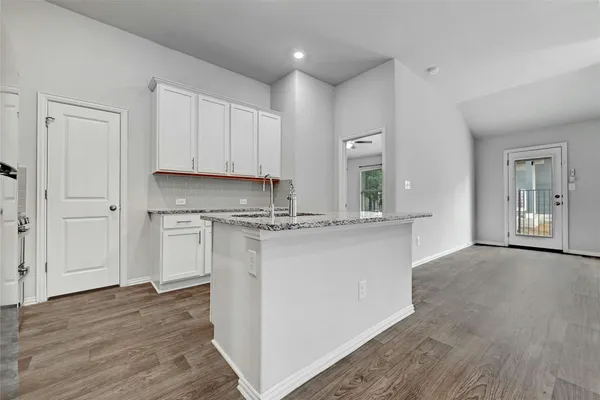 a kitchen with kitchen island granite countertop a refrigerator and a sink