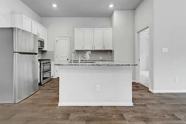 a kitchen with kitchen island granite countertop cabinets and stainless steel appliances