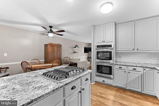 a kitchen with kitchen island granite countertop a sink cabinets and stainless steel appliances