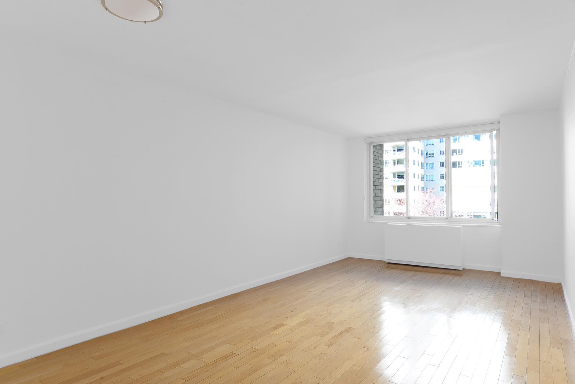 220 East 65th Street, Unit 8J Manhattan, NY 10065 - Photo 8 of 23 an empty room with wooden floor and windows