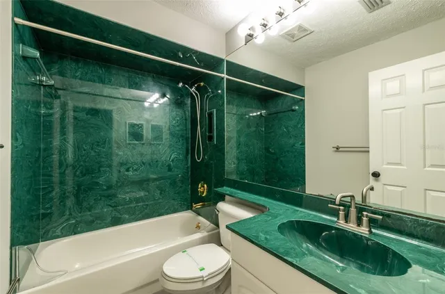 a bathroom with a granite countertop bathtub shower sink mirror vanity and toilet