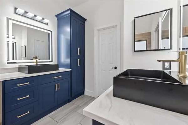 a spacious bathroom with a granite countertop double vanity sink a mirror and a bathtub
