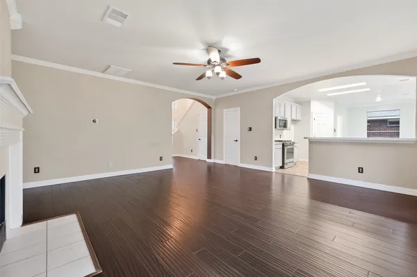 an empty room with wooden floor a ceiling fan a fireplace and windows