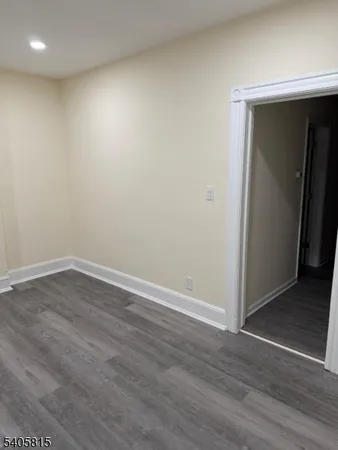 a view of an empty room with wooden floor and closet