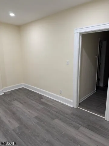 a view of an empty room with wooden floor and closet