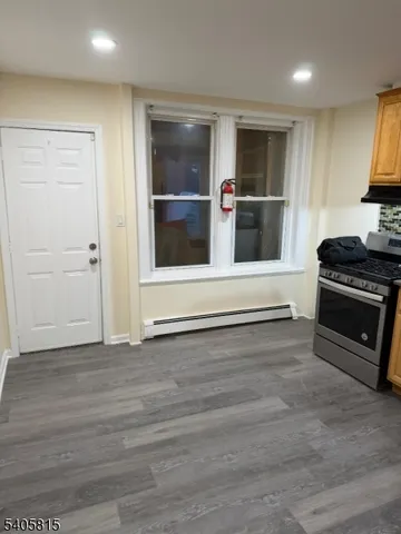 an empty room with wooden floor and kitchen