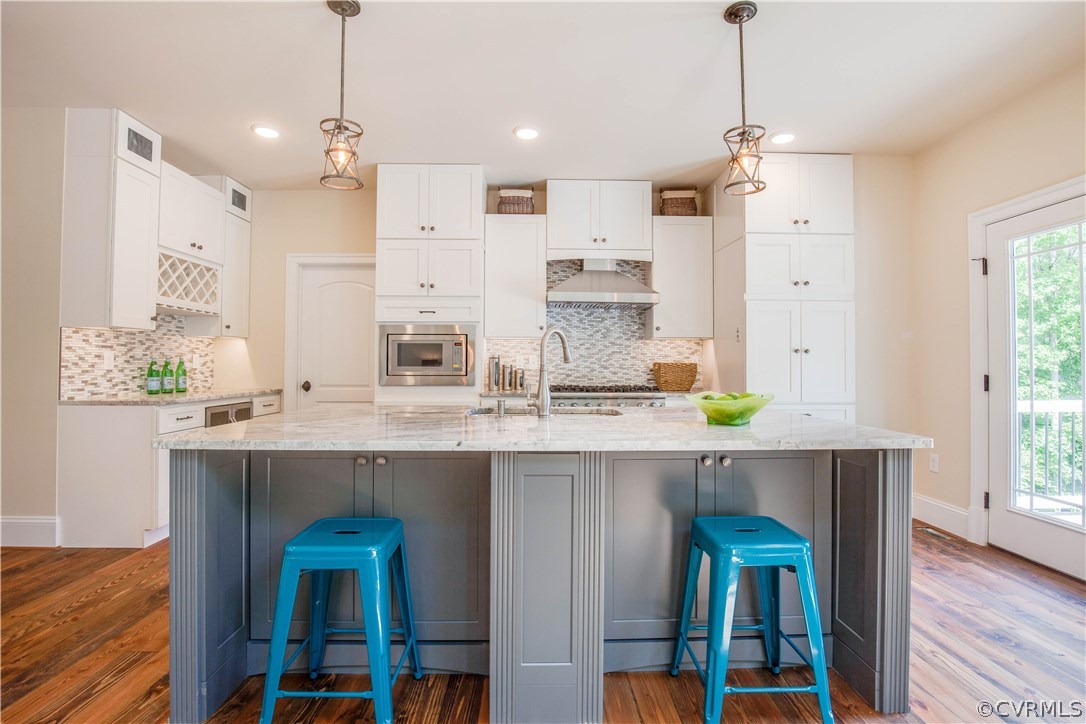 4120 East Old Gun Road Midlothian, VA 23113 - Photo 20 of 25 a kitchen with kitchen island granite countertop wooden floor white cabinets and stainless steel appliances