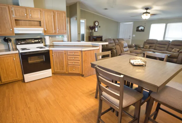 a kitchen with stainless steel appliances kitchen island granite countertop a stove a sink a dining table and chairs