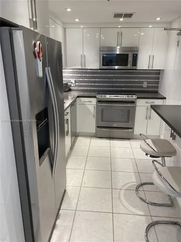 a kitchen with stainless steel appliances granite countertop a refrigerator and a stove top oven