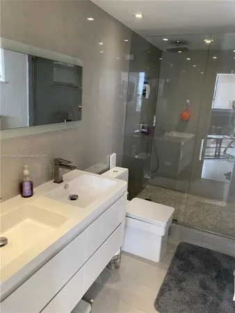 a bathroom with a sink a toilet a mirror and shower