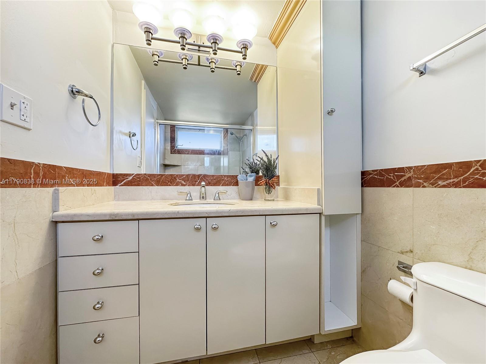 8001 Crespi Boulevard, Unit 7A Miami Beach, FL 33141 - Photo 19 of 25 a bathroom with a sink a toilet and vanity