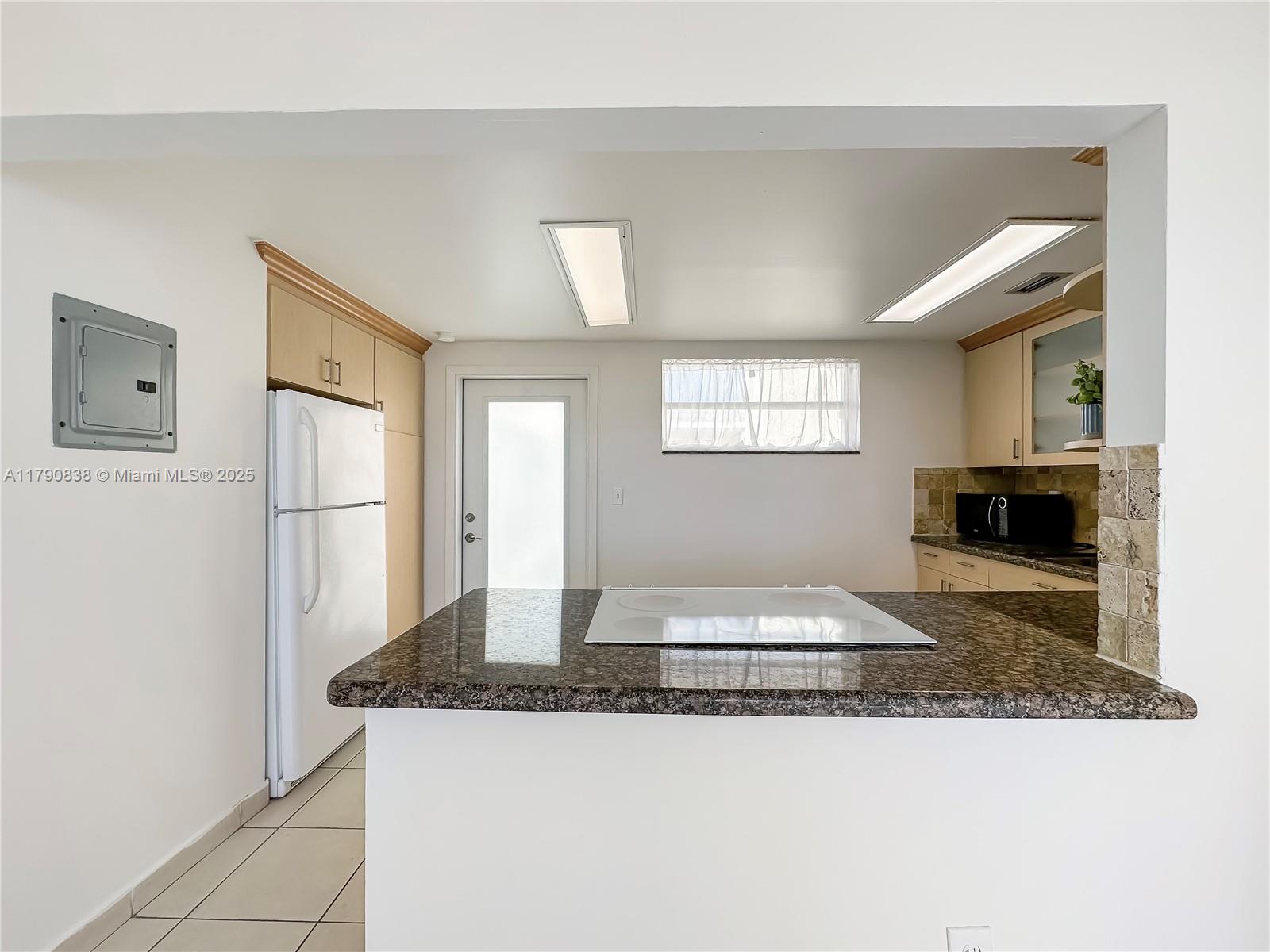 8001 Crespi Boulevard, Unit 7A Miami Beach, FL 33141 - Photo 2 of 25 a kitchen with granite countertop a refrigerator and a stove top oven