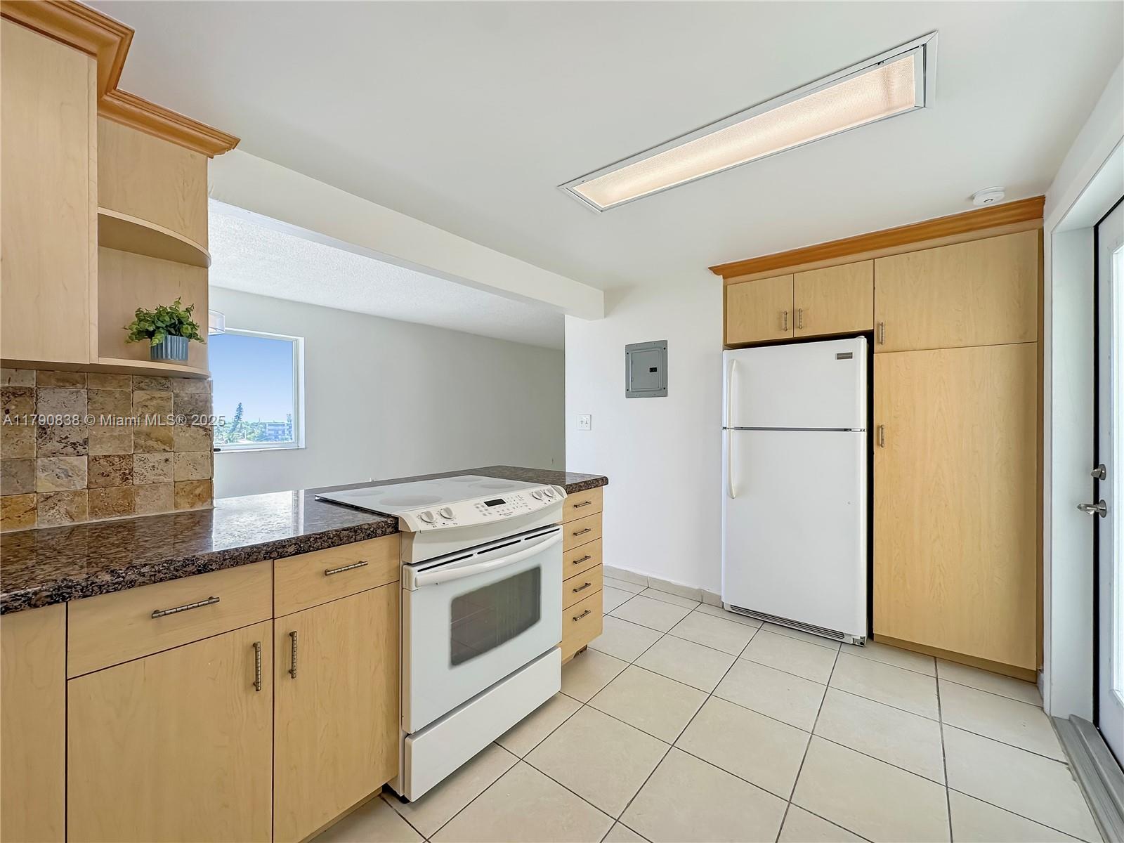 8001 Crespi Boulevard, Unit 7A Miami Beach, FL 33141 - Photo 5 of 25 a kitchen with cabinets a refrigerator and a stove top oven
