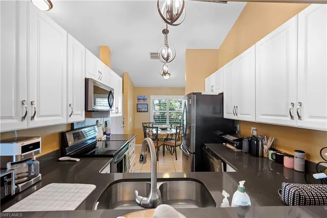 a kitchen with a sink dishwasher a stove a dining table and chairs with wooden floor