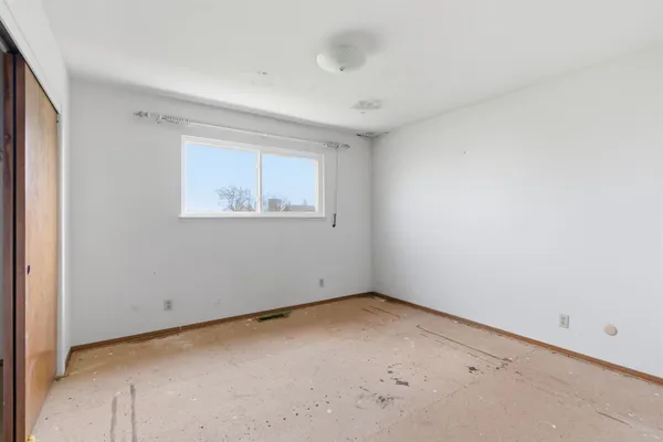 a view of an empty room with closet and a window