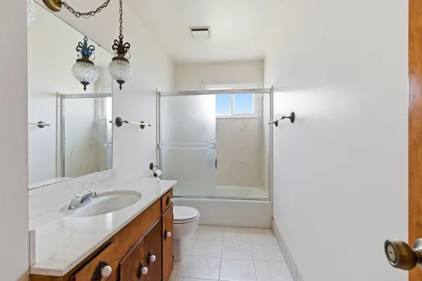 a bathroom with a granite countertop toilet sink and mirror