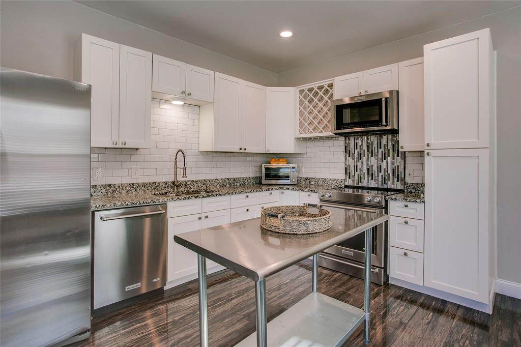 834 South Polk Street Dallas, TX 75208 - Photo 11 of 38 a kitchen with stainless steel appliances granite countertop a stove top oven a sink dishwasher a dining table and chairs with wooden floor