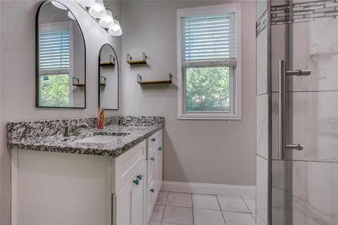 a bathroom with a granite countertop sink a mirror and shower