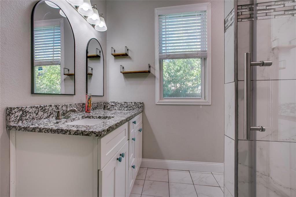 834 South Polk Street Dallas, TX 75208 - Photo 19 of 38 a bathroom with a granite countertop sink a mirror and shower