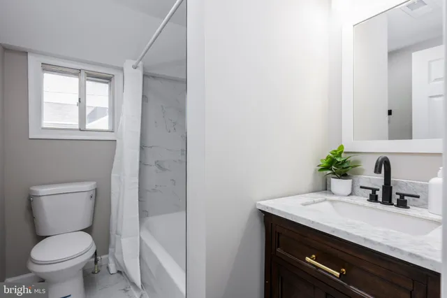 a bathroom with a granite countertop toilet sink and mirror