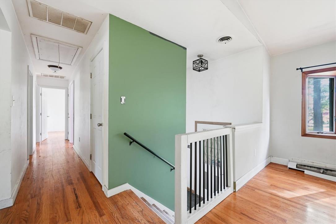 Rich hardwood floors lead past the stairwell into a bright, welcoming hallway.